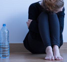 Sad skinny anorectic girl and bottle of water