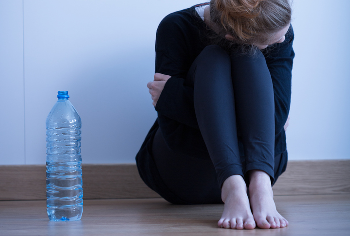 Sad skinny anorectic girl and bottle of water